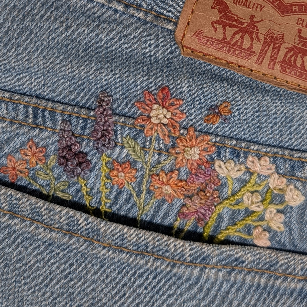 Embroidered floral design on denim fabric with Levi's brand tag.